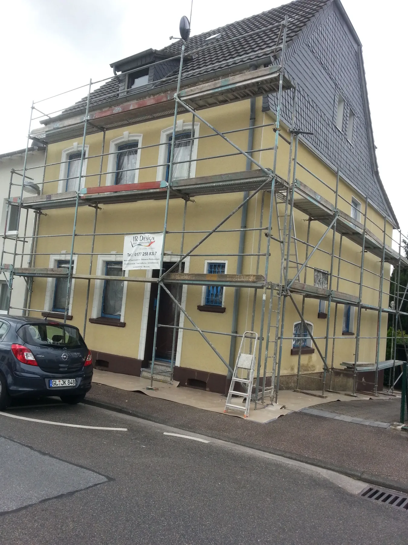 Mehrfamilienhaus im Gerüst mit gelb gestrichener Straßenfassade
