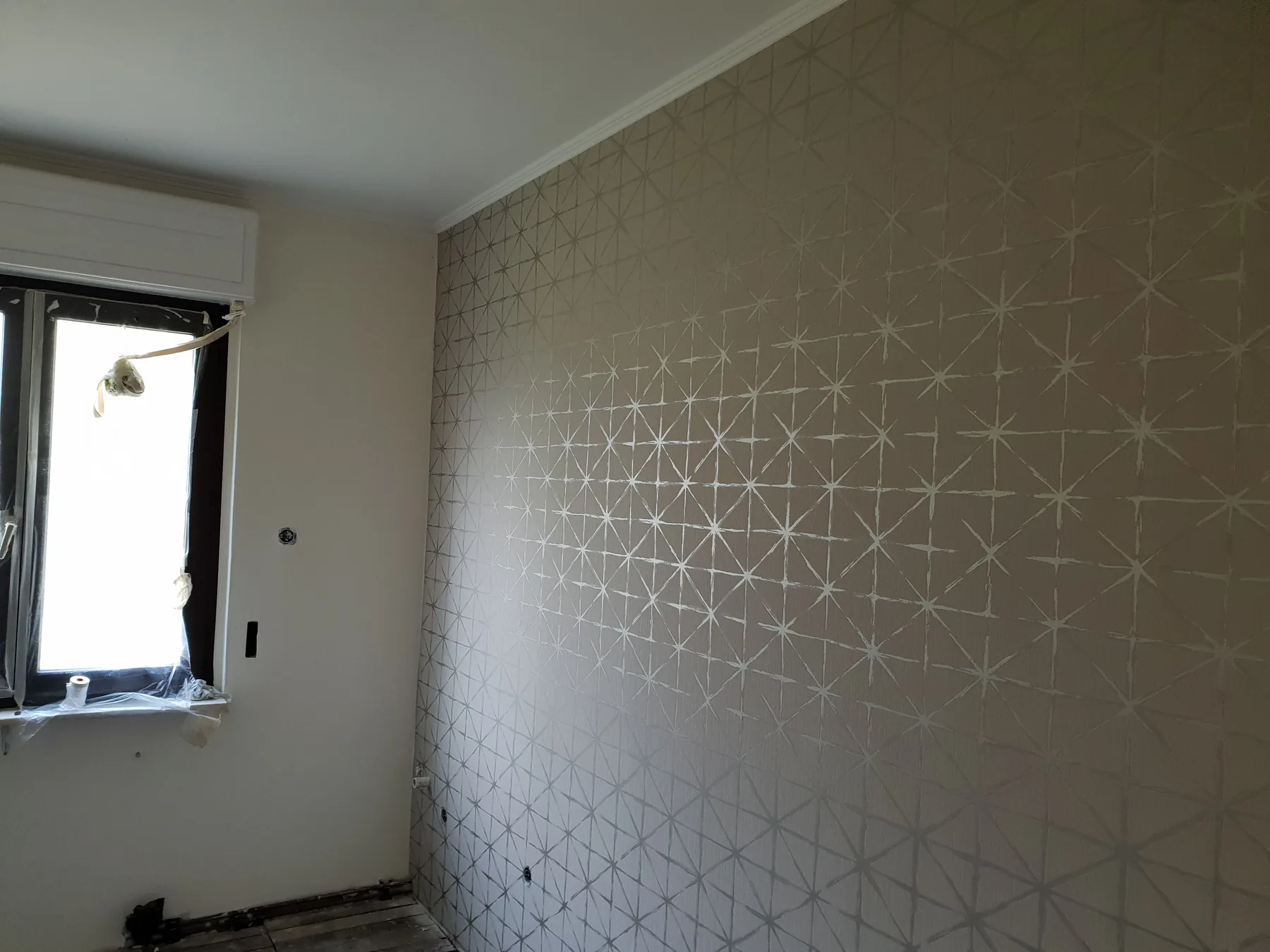 Wand mit grafischer Mustertapete in Silber auf Beige