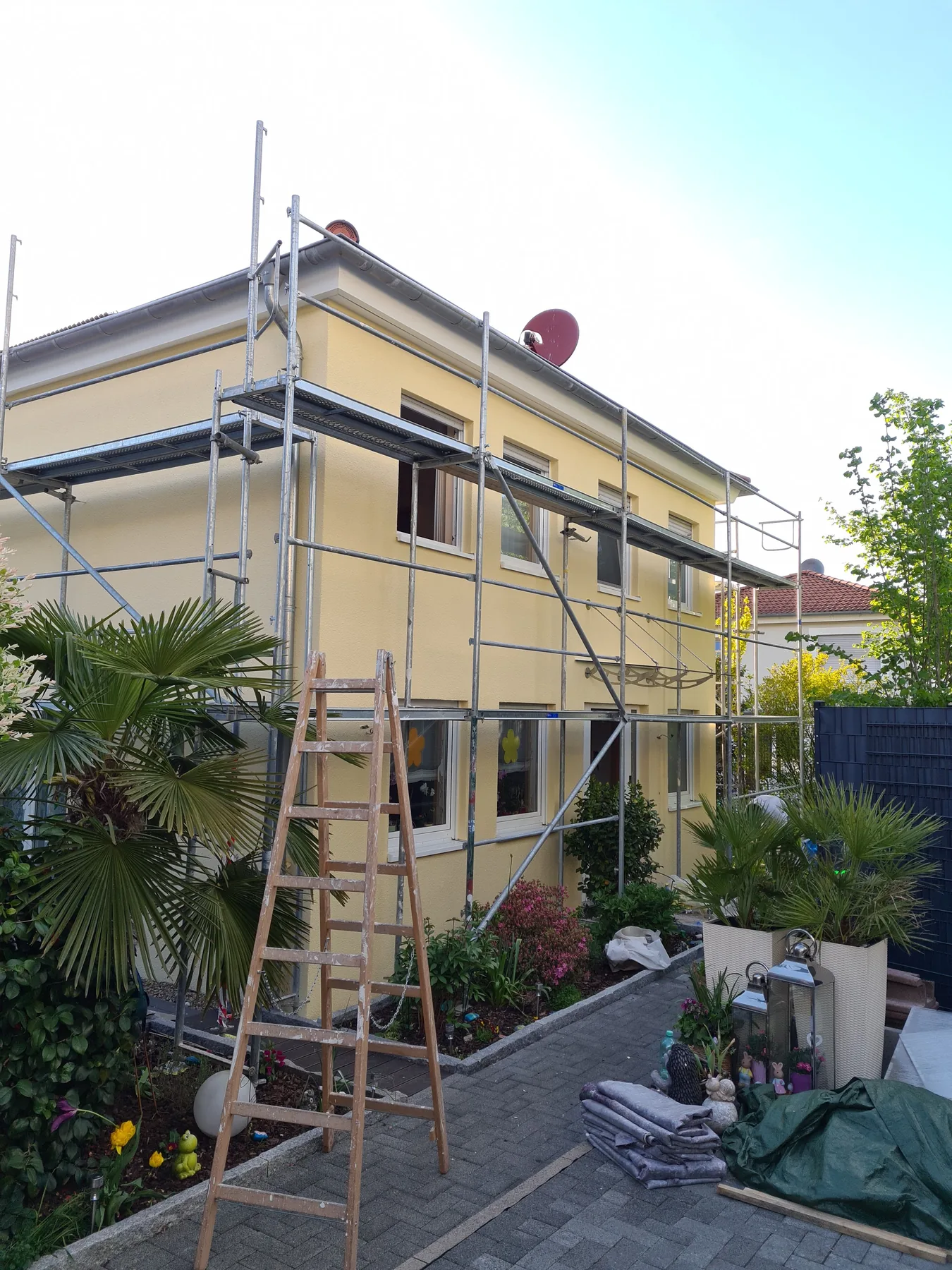 Haus im Gerüst mit frisch gestrichener sandgelber Fassade